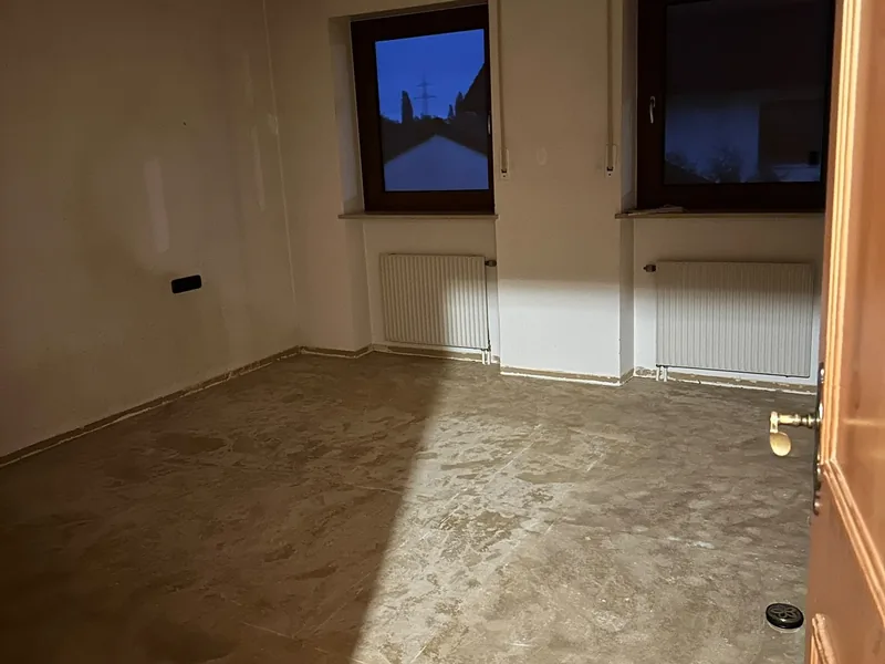 Leeres Zimmer mit zwei Fenstern und Heizkörpern nach der Räumung