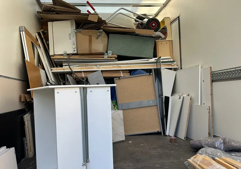 Zwei Träger tragen ein Sofa durch einen hellen Raum
