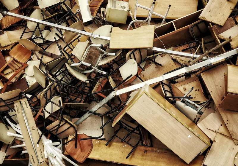 Stapel ausrangierter Holzstühle und Tische zur Abholung