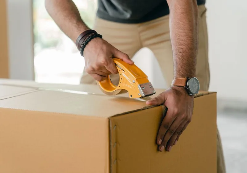 Umzugskarton wird mit Packband verschlossen