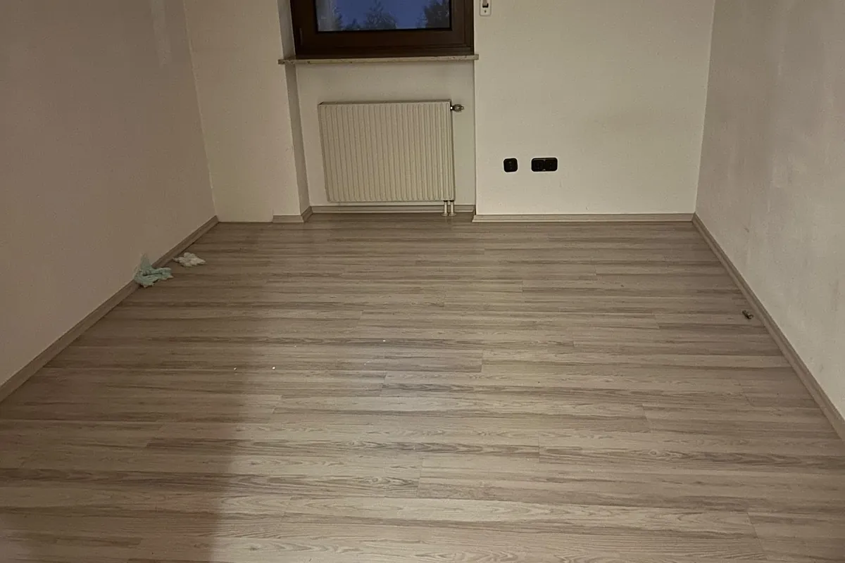 Leeres Zimmer mit Laminatboden nach der Wohnungsauflösung
